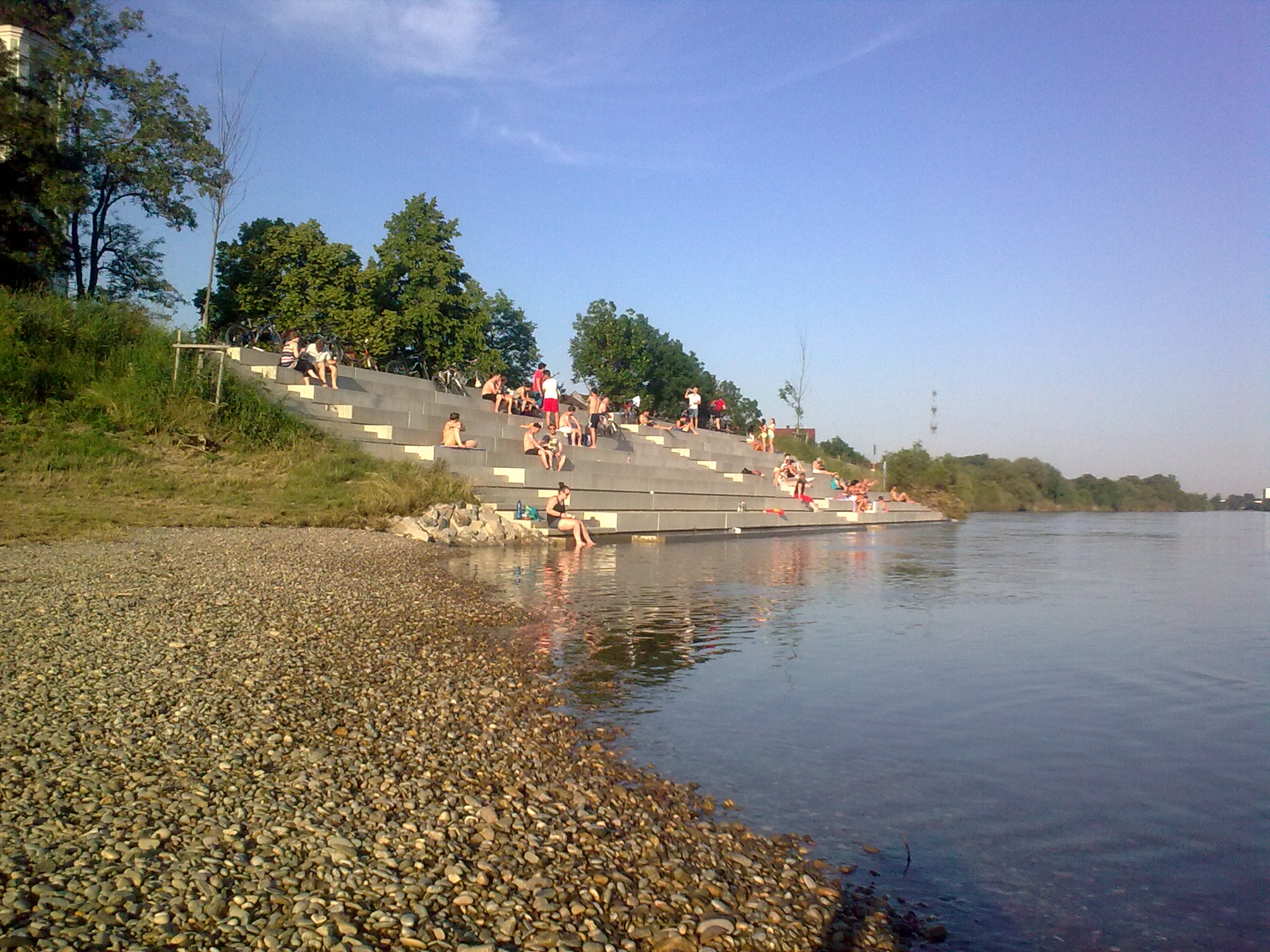 Treppenanlage mit Badegästen, im Vordergrund die Donau und links der Kiesstrand