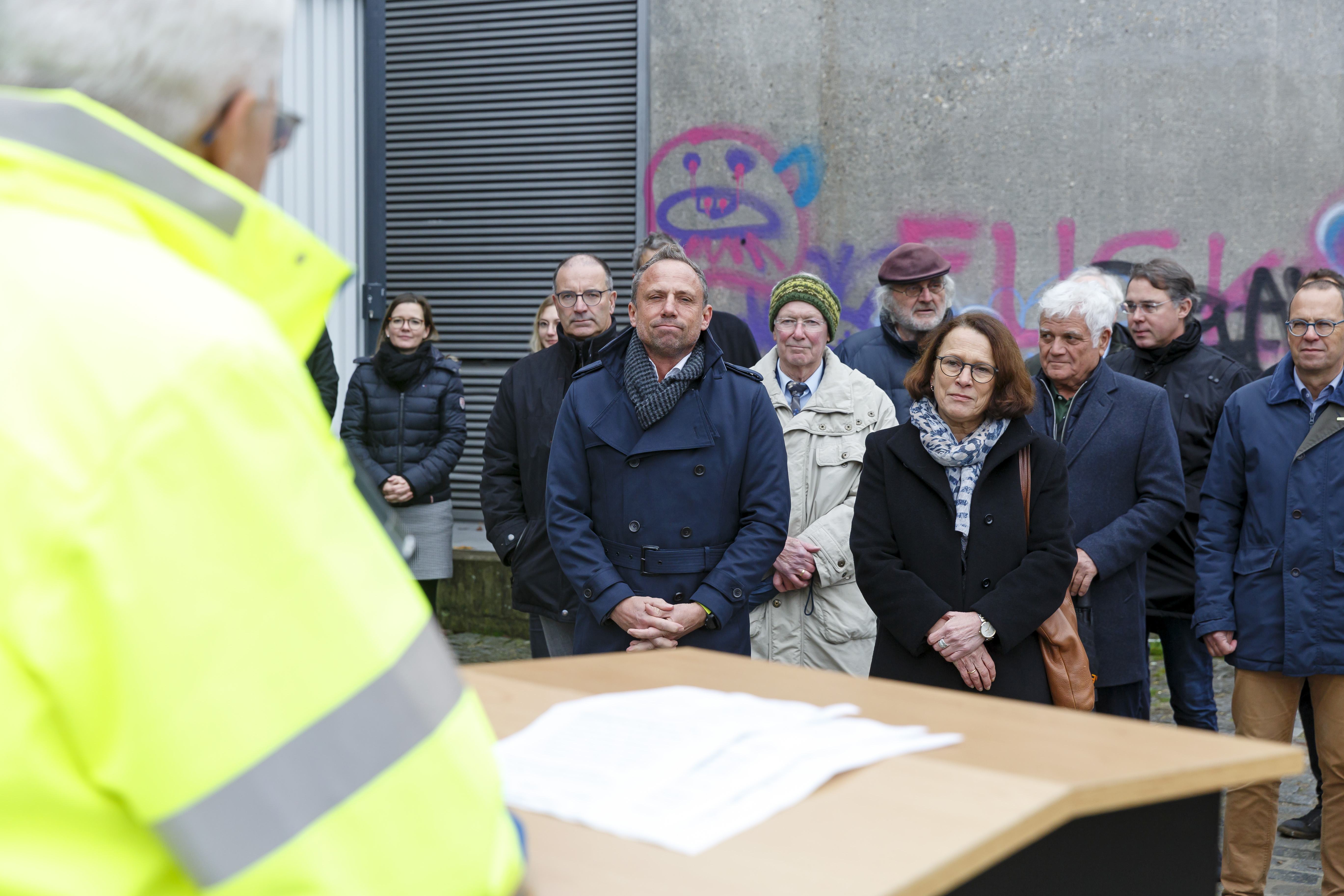 Links im Bild der Behördenleiter des WWAs am Rednerpult, daneben die zuhörenden Gäste. Im Hintergrund das mit Graffiti besprühte Widerlager der Nibelungenbrücke.