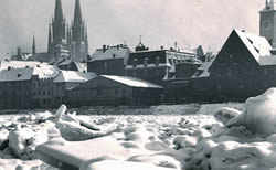 aufgetürmte Eisschollen im Vordergrund; im Hintergrund der Dom und die Steinerne Brücke